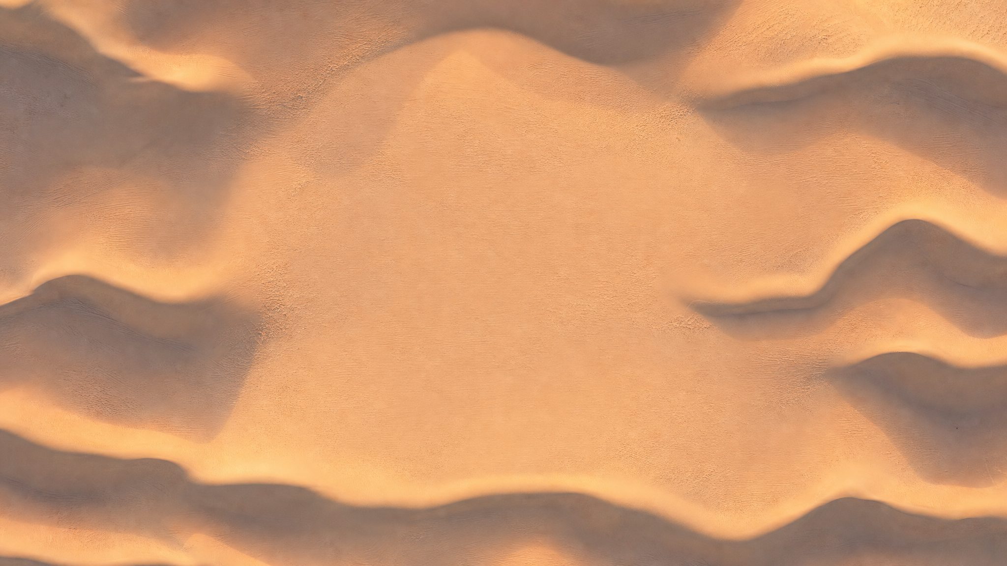 Sand dunes seen from above, with soft wave ridges